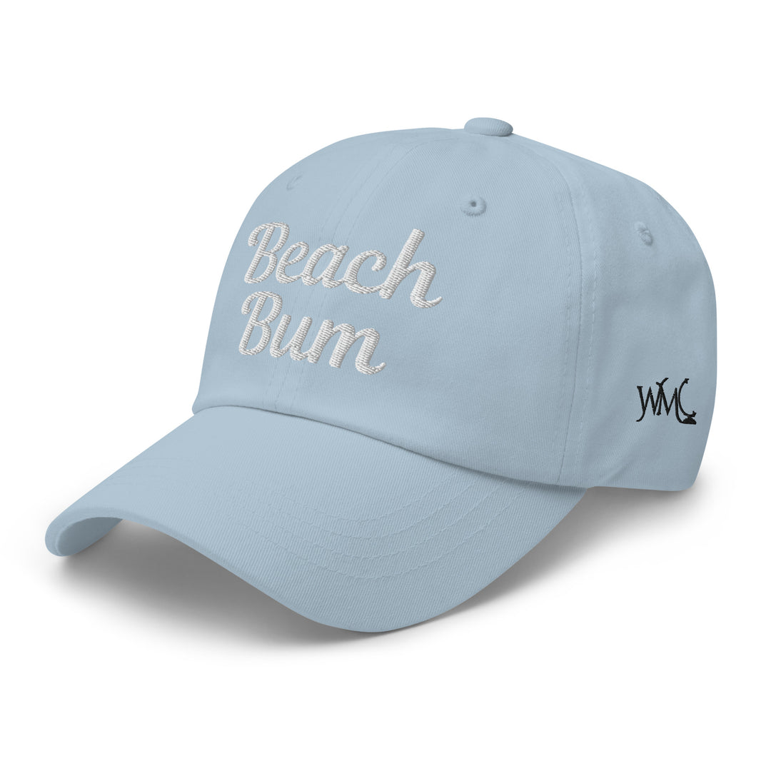 Classic cap with the words "Beach Bum" embroidered in white against a blue background representing the ocean and blue skies of the beach scene.