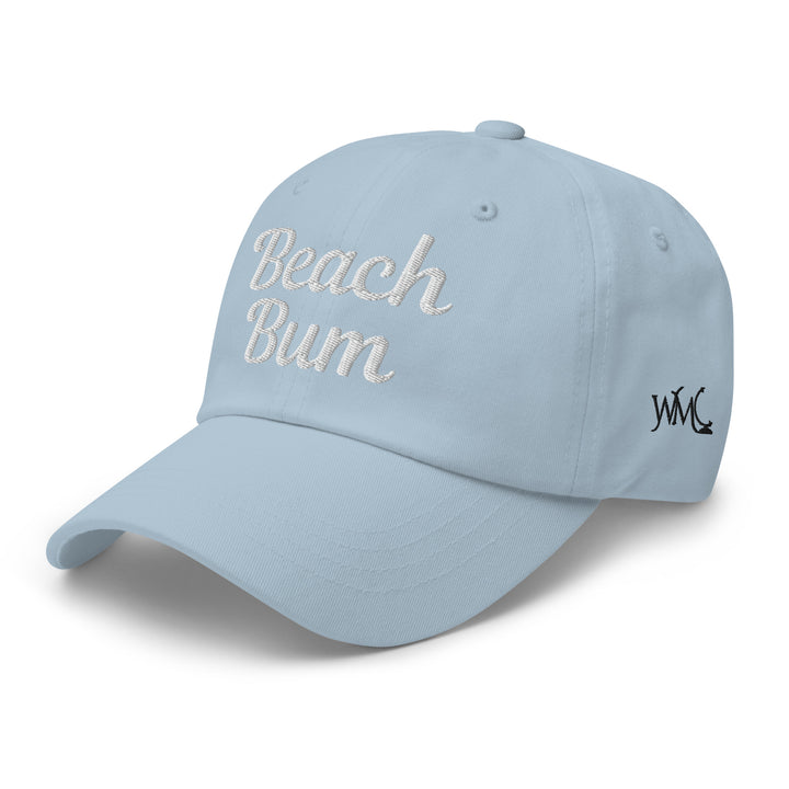 Classic cap with the words "Beach Bum" embroidered in white against a blue background representing the ocean and blue skies of the beach scene.
